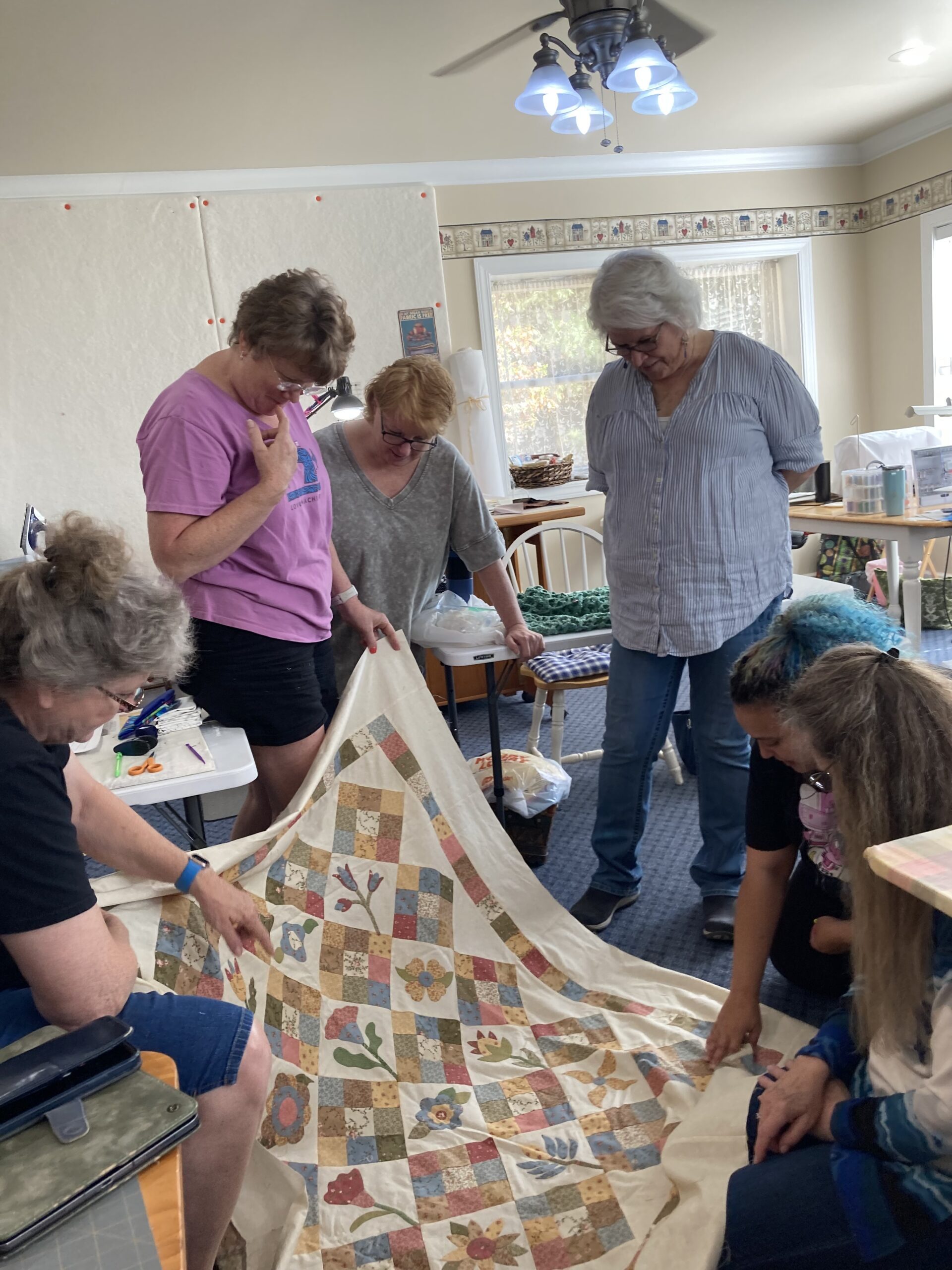 Three ladies examining a quilt.