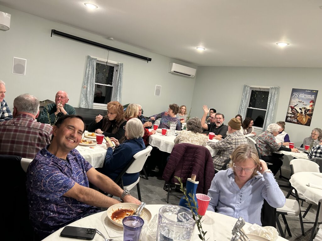 Residents sitting at round tables in the community center.