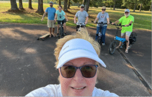 Six people standing over their bicycles waiting to begin riding again. 